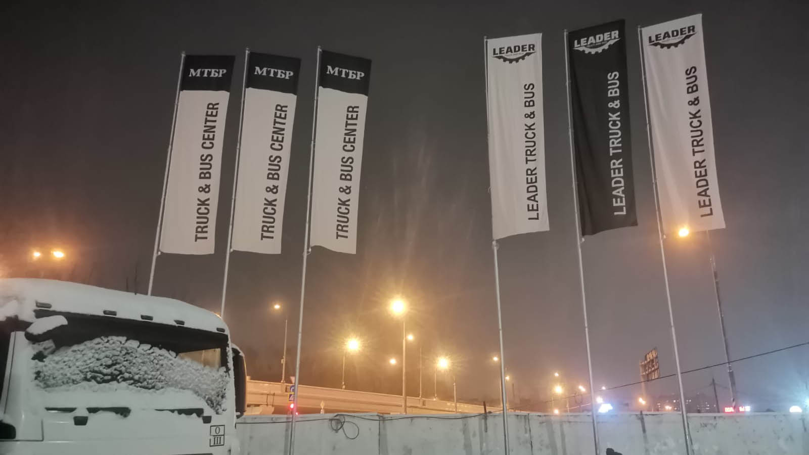 Фото уличных флагштоков с баннерным плечом на парковке в Подмосковье